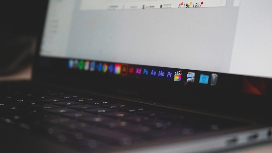 Photograph of a laptop showing design applications in the navigation bar.